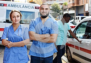 Portrait of smiling male and female paramedicals near ambulance car