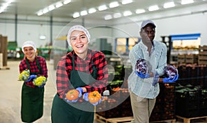 Portrait of smiling male and female workers posing and having fun at warehousing with crop of vegetable