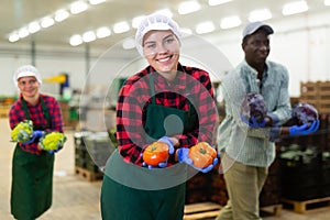 Portrait of smiling male and female workers posing and having fun at warehousing with crop of vegetable