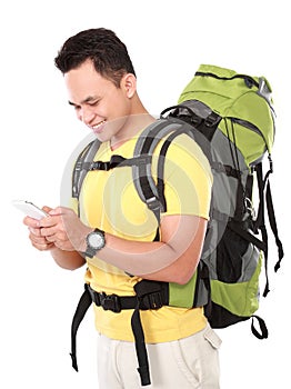 portrait of a smiling male hiker with backpack using mobile phone