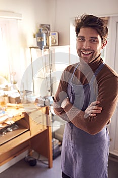 Portrait Of Smiling Male Jeweller At Bench Working In Studio