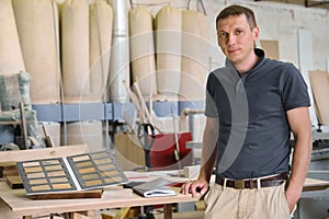 Portrait of smiling male owner of industrial small business woodworking workshop, man looking at the camera