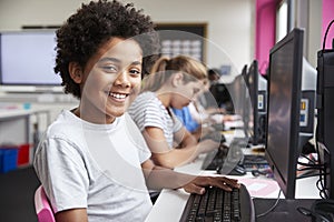 Portrait Of Smiling Male Pupil Sitting In Line Of High School Students Working at Screens In Computer Class