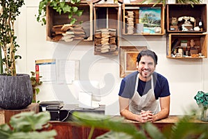 Portrait Of Smiling Male Sales Assistant Standing Behind Sales Desk Of Florists Store