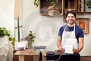 Portrait Of Smiling Male Sales Assistant Standing Behind Sales Desk Of Florists Store