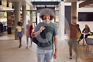 Portrait Of Smiling Male Student In Busy University Or College Building