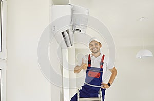 Portrait of smiling male technician showing thumb up after commissioning air conditioner. photo