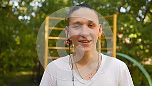 Portrait of smiling male teenager with headphone looking into the camera outdoors. Close up shot.