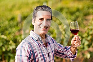 Portrait of smiling male vintner holding a glass of wine