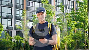Portrait smiling man courier food delivery with thermal backpack uses tablet