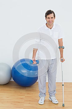 Portrait of a smiling man with crutch and dumbbell