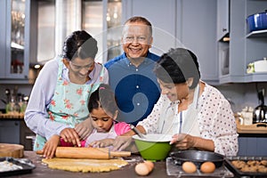 Portrait of smiling man with family preparing food in kitchen