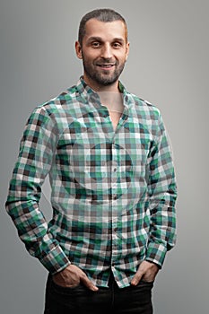 Portrait of a smiling man in a green plaid shirt on a gray background