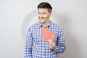 Portrait of smiling man holding red paper pixel heart