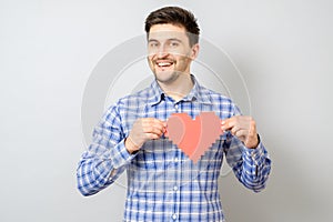 Portrait of smiling man holding red paper pixel heart