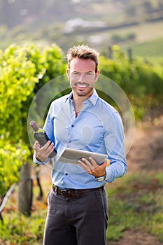 Portrait of smiling man holding wine bottle and tablet