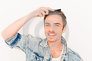 Portrait of smiling man in jeans jacket combing his hair