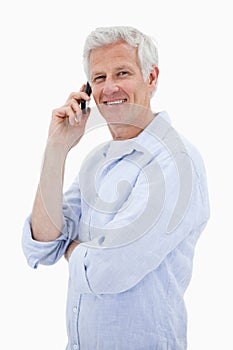 Portrait of a smiling man making a phone call while looking at t