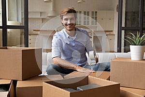 Portrait of smiling man pack boxes relocating to new home photo