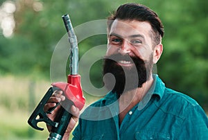 Portrait of a smiling man refueling car at the gas station. Man on petrol pump filling nozzles. Gas station. Portrait of