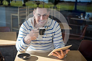 Portrait of smiling man using digital tablet while having coffee