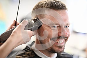 Portrait of smiling man whose master cuts with machine.