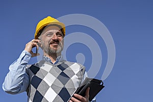 Portrait of Smiling Manager with Mobile Phone and Digital Tablet Against The Blue Sky