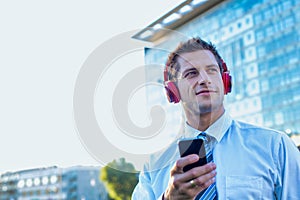 Portrait of smiling mature businessman listening to music on his smartphone with headphones on