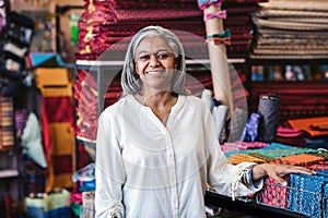 Smiling mature woman standing by cloth in her fabric store