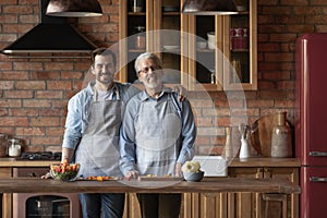 Portrait smiling mature father with grownup son standing in kitchen