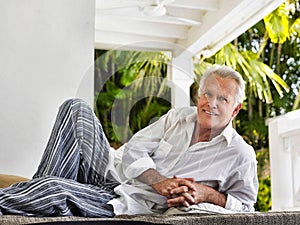 Portrait of a smiling mature man reclining on verandah