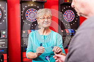 Mature woman holding dartboard arrows