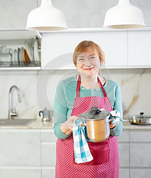 Portrait of a smiling mature woman with a saucepan in her hands