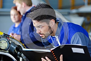 Portrait smiling mechanic in workshop holding book