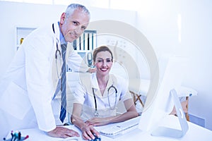 Portrait of smiling medical colleagues working with computer and looking at camera