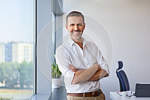 Portrait of smiling mid adult businessman standing at office