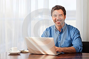 A portrait of a smiling middle-aged bearded man on a window background