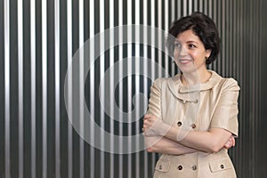 Portrait of smiling middle aged business woman with crossed arms on a striped wall background.