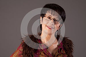 Portrait of a smiling middle aged caucasian woman against grey background.