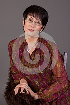 Portrait of a smiling middle aged caucasian woman against grey background.