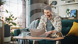Portrait of Smiling Middle Aged Man Working from Home on a Laptop Computer in Sunny Cozy Apartment