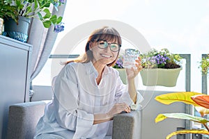 Portrait of smiling middle-aged woman with glass of water, at home