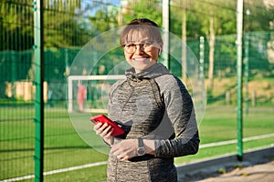 Portrait of smiling middle aged woman looking at camera at sports outdoor stadium