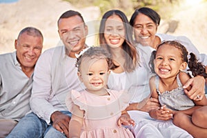 Portrait of a smiling mixed race family with little girls sitting together at the beach. Adorable little kids bonding