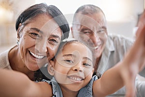 Portrait of smiling mixed race grandparents and granddaughter taking a selfie in the lounge at home. Hispanic senior man