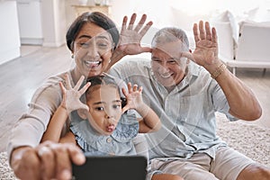 Portrait of smiling mixed race grandparents and granddaughter taking a selfie in the lounge at home. Hispanic senior man