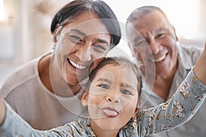 Portrait of smiling mixed race grandparents and granddaughter taking a selfie in the lounge at home. Hispanic senior man