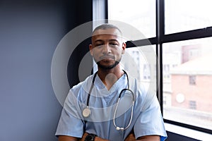 Portrait of smiling mixed race male doctor wearing scrubs and stethoscope