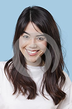 Portrait of smiling mixed race young woman over blue background