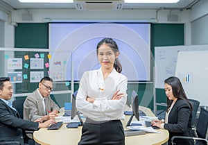 Portrait smiling modern business woman standing in an office at team meeting. Confident young Asian businesswoman with colleagues